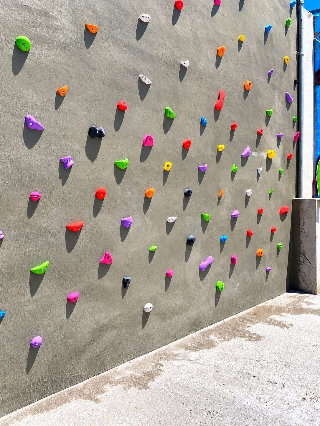 Rocódromo con presas de colores sobre una pared gris.