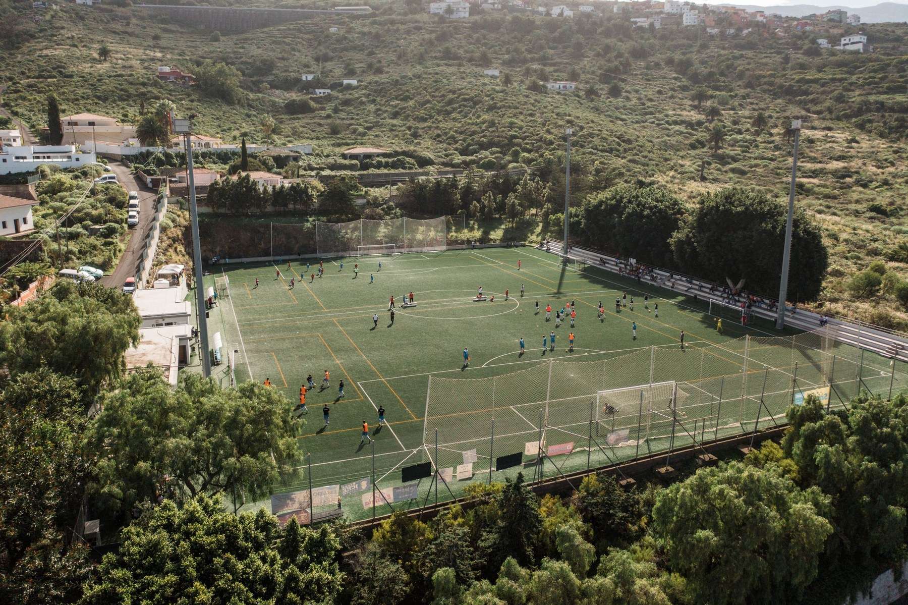 Campo de fútbol en la ladera de El Sauzal, rodeado de vegetación y casas.